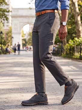 Black tailored dress slacks paired with a micro-print blue dress shirt and a tan leather belt that coordinates with the shoe's welt and tongue detail.