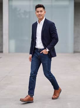 Slim-fit dark wash denim jeans, a crisp white button-down Oxford shirt, and a navy unconstructed wool blazer.