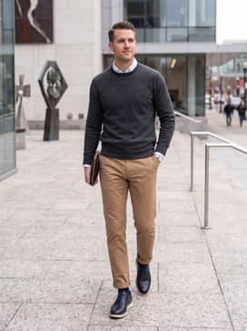 Khaki or tan trousers worn with a charcoal grey cashmere sweater and a white undershirt for a refined seasonal transition outfit.