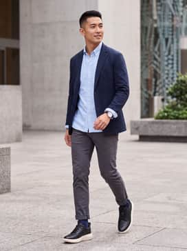 A pair of charcoal slim-fit chinos paired with a crisp light-blue button-down oxford shirt and a navy unconstructed blazer for a polished office-to-dinner transition.
