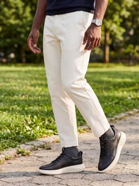 Grey tailored trousers cropped at the ankle, paired with a fitted white polo shirt and a minimalist silver wristwatch to emphasize the shoe's modern silhouette.