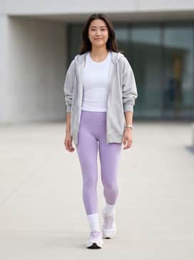 High-waisted lavender leggings paired with a white cropped performance tank and an oversized light-grey zip-up hoodie for a cohesive gym-to-street look.