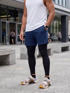 Navy 7-inch athletic shorts worn over black base-layer tights and topped with a breathable white mesh tank to keep the focus on the footwear.