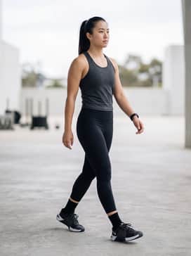 High-waisted black compression leggings paired with a moisture-wicking charcoal racerback tank and a sleek high ponytail for an intense HIIT session.