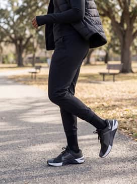 Metcon 10 – Dark slim-fit track pants with a quarter-zip technical pullover and a lightweight puffer vest for outdoor morning warm-ups.