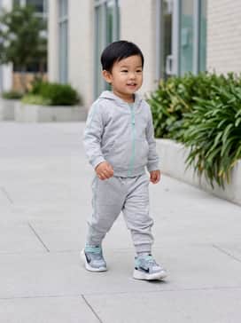 A soft grey cotton tracksuit featuring mint green piping on the sleeves to match the sneaker's teal accents, providing a comfortable and coordinated look for daycare.
