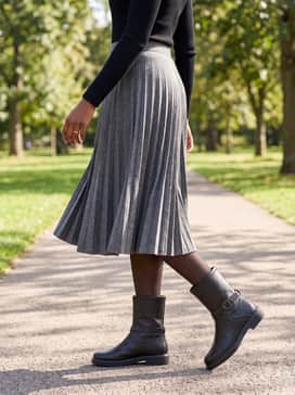 A grey pleated wool midi skirt, a black ribbed long-sleeve top, and sheer black tights for a sophisticated, weather-appropriate ensemble.