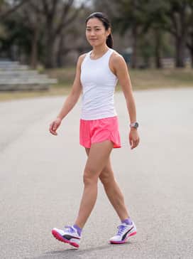 Professional race kit featuring a moisture-wicking white compression singlet paired with neon pink split running shorts for a high-visibility, coordinated track look.