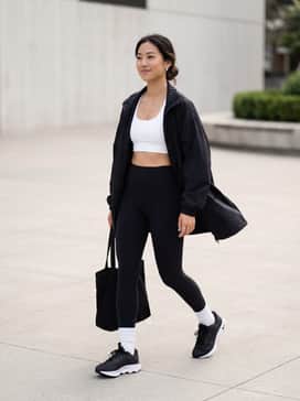 Motiva – A sleek monochromatic look featuring high-waisted black leggings, a white cropped sports bra, and an oversized black windbreaker for a modern gym-to-street transition.