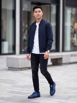 Distressed black slim-fit jeans paired with a crisp white graphic tee and an unzipped navy bomber jacket for a cohesive, street-ready look.