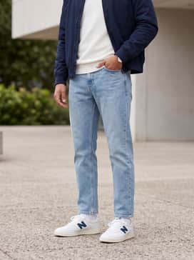 Light-wash straight-leg denim jeans with a simple white crewneck sweater and a navy blue bomber jacket to match the sneaker accents.