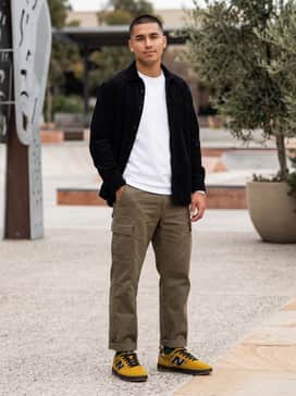 Straight-leg olive cargo trousers matched with a crisp white heavyweight t-shirt and an unbuttoned black corduroy shirt for a rugged, textured streetwear aesthetic.