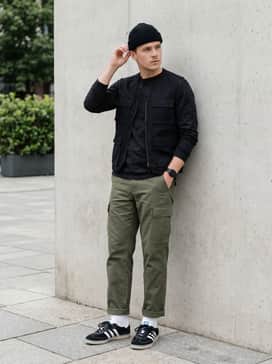 Newcastle Spzl Fc Shoes – Olive green cargo trousers with a tucked-in black long-sleeve graphic t-shirt and a matching black beanie for a utilitarian street vibe.