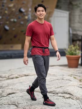 Niad Moccasym Climbing Shoes – A technical climbing outfit featuring charcoal moisture-wicking joggers, a crimson performance t-shirt, and a chalk bag belt for a focused bouldering session.