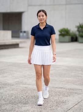 A pleated white tennis skirt paired with a fitted navy polo shirt for a classic on-court aesthetic.