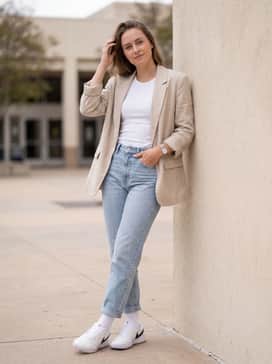 Light-wash high-rise denim jeans, a simple white tank top, and an oversized beige linen blazer for a polished yet casual street look.