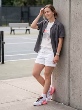 Distressed light-wash denim shorts and an oversized white graphic tee for a relaxed, sporty-casual summer look.