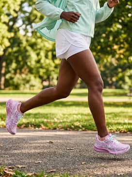 Noosa Tri 16 – White athletic shorts with a mesh overlay, a mint green sports bra to pick up the lace color, and an open lightweight windbreaker for a fresh, warm-weather workout outfit.