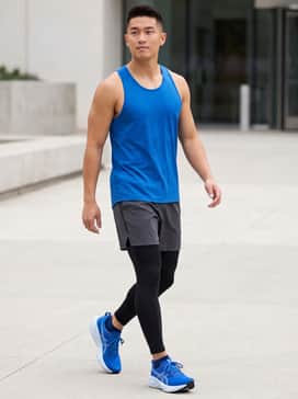 A high-performance look featuring black compression tights worn under charcoal grey five-inch running shorts, paired with a matching electric blue moisture-wicking racerback tank for maximum mobility.