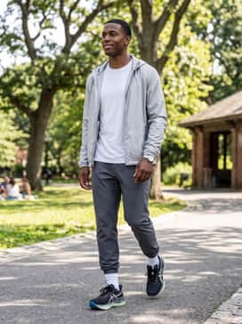 A weekend casual outfit featuring slim-fit dark wash stretch denim, a premium white t-shirt, and a lightweight silver windbreaker to accent the shoe's branding.