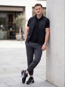 Novablast 5 Platinum – A sleek athleisure look comprising charcoal grey tapered sweatpants, a fitted black performance polo shirt, and a lightweight silver-grey quilted vest.