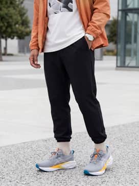 Black tapered joggers and a white oversized graphic tee, layered with an orange windbreaker that echoes the shoe's side gradient.