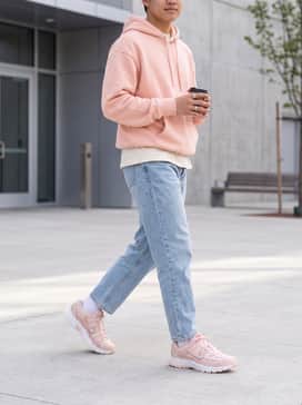 Light-wash high-waisted mom jeans paired with a tucked-in white graphic tee and an oversized pastel pink hoodie for a cohesive, relaxed look.