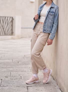 Beige cargo pants with a cropped white ribbed tank top and a light-wash denim jacket, creating a trendy urban utility vibe.