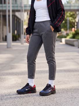 Grey tapered joggers worn with a white athletic tank top and a black and red track jacket for a coordinated sporty look.