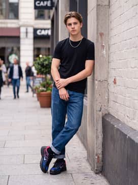 Relaxed fit distressed denim jeans cuffed at the bottom, styled with a plain black tee and a silver chain necklace.