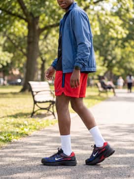 Red mesh athletic shorts paired with a blue windbreaker and tall white crew socks to emphasize the retro runner aesthetic.