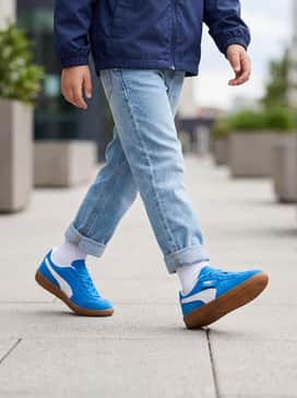 Light-wash straight-leg denim jeans cuffed at the ankle, paired with a crisp white graphic t-shirt and a navy blue lightweight windbreaker for a classic school look.