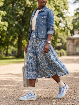 A ditsy floral midi sundress in shades of blue and cream, topped with a distressed denim jacket for a perfectly balanced feminine-sporty daytime look.