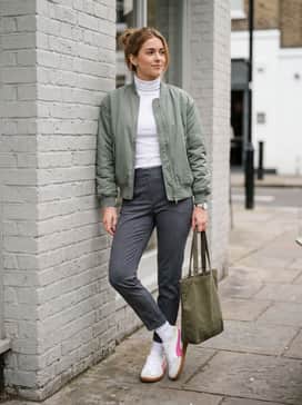 Grey tailored joggers worn with a fitted white turtleneck and a sage green bomber jacket for a clean, modern athletic ensemble.