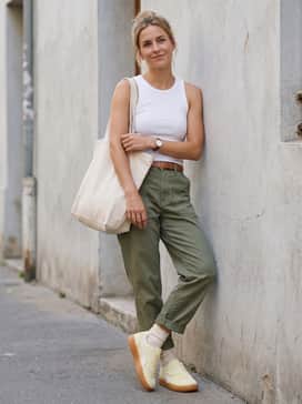 Style with olive green utility trousers, a fitted white ribbed tank top, and a large canvas tote for a practical and trendy weekend outfit.