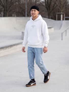 Relaxed-fit light wash denim jeans, a white oversized graphic hoodie, and a black beanie for a classic skate-ready look.