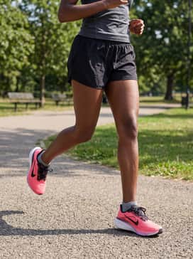 Reflective black running shorts and a neon pink ventilated t-shirt, paired with no-show athletic socks and a white performance baseball cap for early morning visibility.