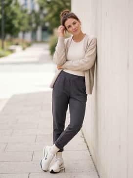 Elevated Athleisure: Style with charcoal grey tapered joggers, a ribbed beige bodysuit, and a loose-knit cream cardigan for a layered look.