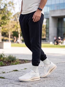 A fitted compression base layer under a lightweight mesh tank top, styled with tapered black joggers and a sleek silver fitness tracker.