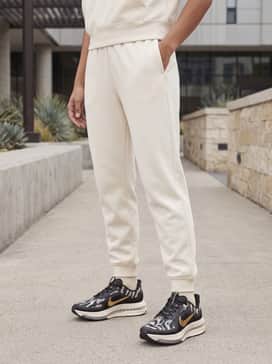Tapered cream-colored joggers and a fitted black technical zip-up jacket for a coordinated and sophisticated pre-run look.