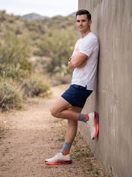 Pegasus Trail 5 Goretex – Navy blue 5-inch inseam running shorts, a technical white t-shirt with orange graphic details, and high-performance quarter-length socks for a professional trail-ready look.