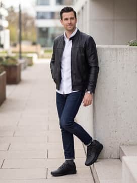 A refined weekend outfit consisting of slim-fit dark indigo raw denim jeans, a crisp white button-down shirt, and a premium black leather racer jacket.