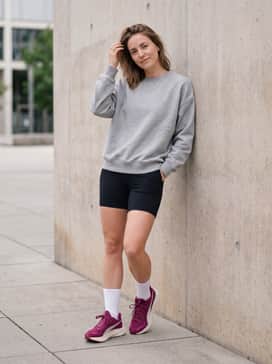 Street-style athleisure ensemble with black biker shorts, an oversized heather grey graphic sweatshirt, and sleek crew socks.