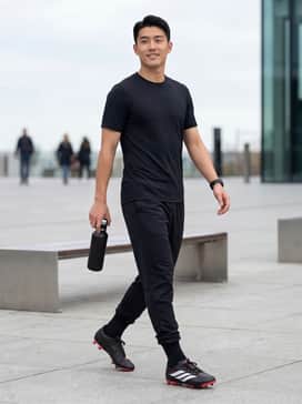 A full team kit featuring a black moisture-wicking jersey, matching athletic shorts, and knee-high black socks that allow the solar red soles to stand out.