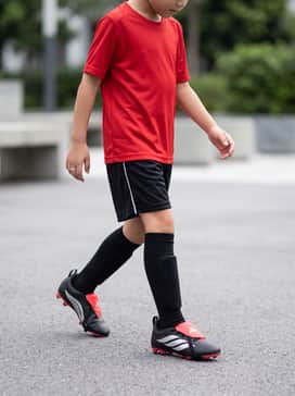 Predator Club Foldover Tongue Elastic Laces Firm Groundmulti Ground Football Boots Kids – A full team match-day kit consisting of a vibrant red performance jersey, matching black soccer shorts with white side-piping, and tall black compression socks pulled up to the knee.