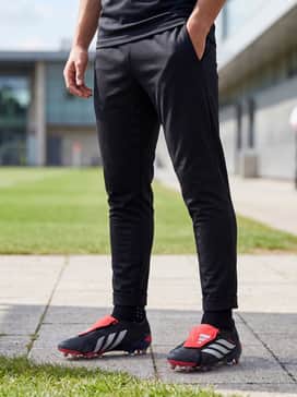 A professional training look consisting of a silver quarter-zip drill top, tapered black tech pants, and low-profile grip socks that allow the fold-over tongue to remain the focal point.