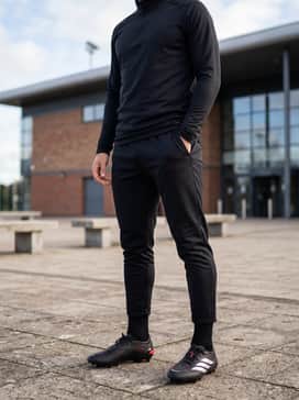 A streamlined training outfit consisting of a black compression base layer, a technical quarter-zip pullover, and tapered athletic joggers.