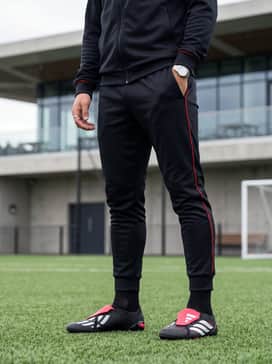 Predator League Foldover Tongue Artificial Ground Football Boots – A sleek all-black training tracksuit with red piping that complements the boot's secondary color accents.