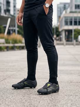 A technical training look with a slim-fit charcoal gray tech hoodie, tapered black track pants with ankle zips, and a bright yellow base-layer tee to match the accents.