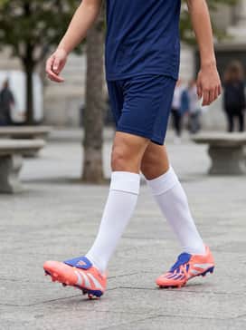 Predator League Foldover Tongue Firmmultiground Cleats Kids – A navy blue moisture-wicking team jersey paired with matching athletic shorts and white knee-high soccer socks to let the vibrant peach color pop.